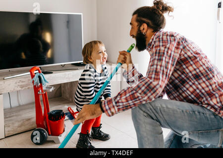 Father and little daughter having fun together while cleaning the living room Stock Photo