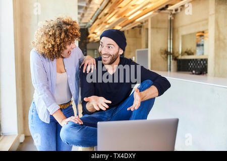 Excited man and woman with laptop in modern office Stock Photo