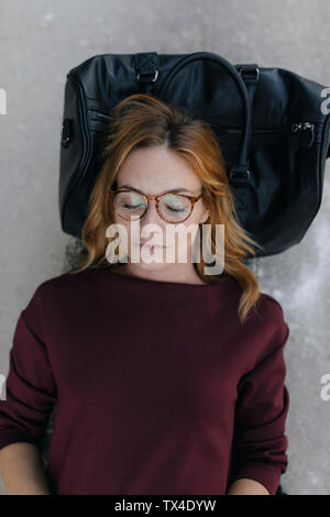 Portrait of young woman sleeping on bag Stock Photo