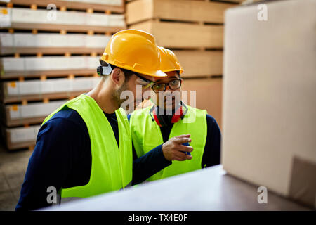 Two workers talking in factory warehouse Stock Photo