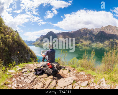 Italy, Lombardy, spring at Lake Idro, hiker sitting with map at observation point Stock Photo