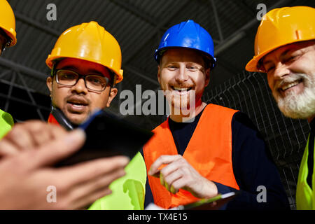 Happy workers in factory warehouse talking and using tablet Stock Photo