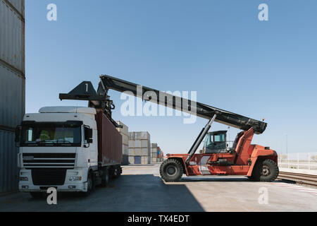 Crane lifting cargo container on truck on industrial site Stock Photo