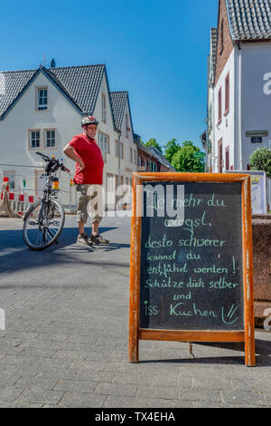 Germany, Zons, senior man with bicycle having a rest Stock Photo