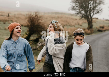 UK, Scotland, Isle of Skye, three happy young woman on a rural road Stock Photo