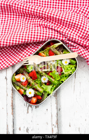 Lunchbox with green salad, green asparagus, strawberries and daisies Stock Photo