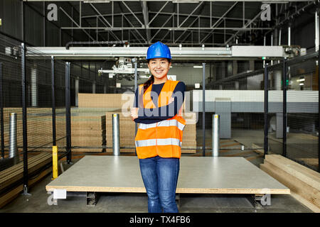 Portrait of smiling female worker in factory warehouse Stock Photo