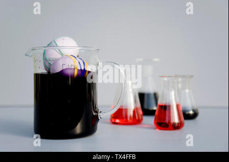 Eggs dyed with rubber bands and purple natural colour in measuring flask Stock Photo