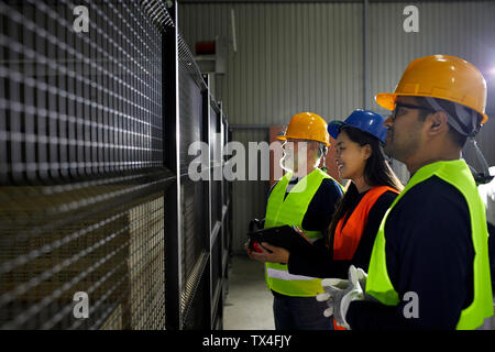 Smiling workers standing at grid in factory Stock Photo