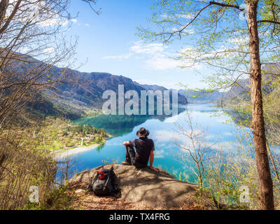 Italy, Lombardy, spring at Lake Idro, hiker sitting on observation point Stock Photo