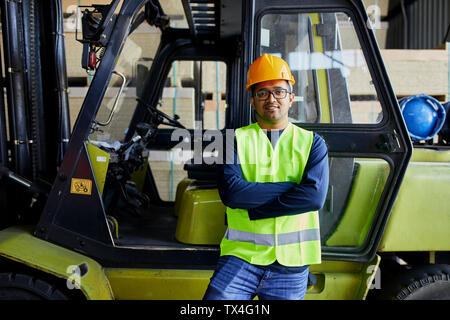 Portrait of confident worker at forklift in factory Stock Photo