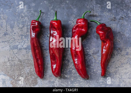 Row of four red pointed peppers Stock Photo