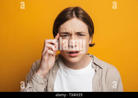 Young handsome man in shirt looking at the camera with poor eyesight over yellow background Stock Photo