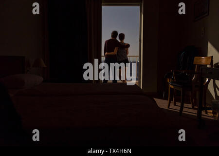 Greece, couple standing on balcony at night with view to the sea Stock Photo