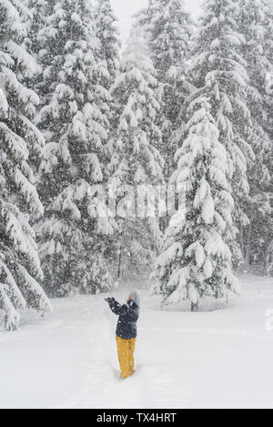 Finland, Kuopio, woman catching snowflakes in winter forest Stock Photo