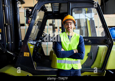 Portrait of confident worker at forklift in factory Stock Photo
