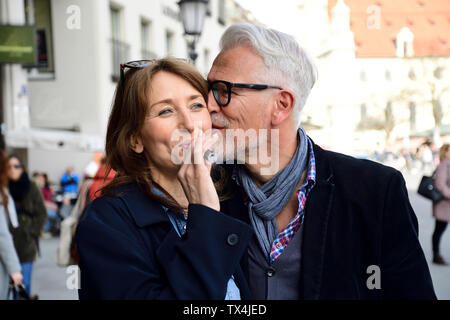 Mature couple walking in the city, woman smoking electronic cigarette Stock Photo