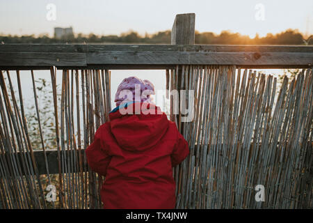 Rear view of toddler girl in warm clothes at a lake Stock Photo