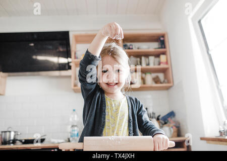 Portrait of smilingl ittle girl rolling out dough in the kitchen Stock Photo