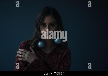 Portrait of young woman wearing Christmas baubles as earrings Stock Photo