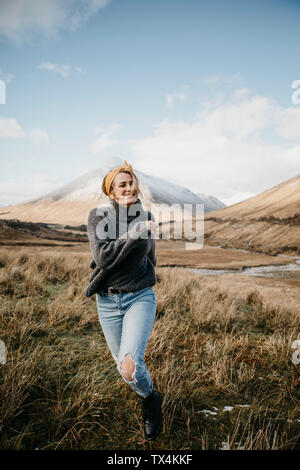 UK, Scotland, Loch Lomond and the Trossachs National Park, happy young woman running in rural landscape Stock Photo