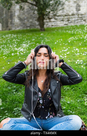 Young woman with white headphones, wearing black leather jacket Stock Photo