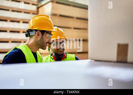 Two workers talking in factory warehouse Stock Photo