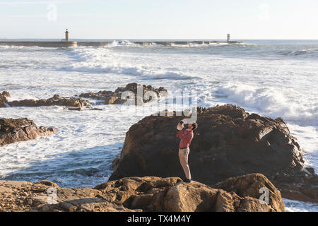 Portugal, Porto, young man standing on rock with his dog Stock Photo