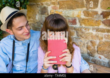 Young couple on a city break, sitting on a bench, reading guidebook Stock Photo