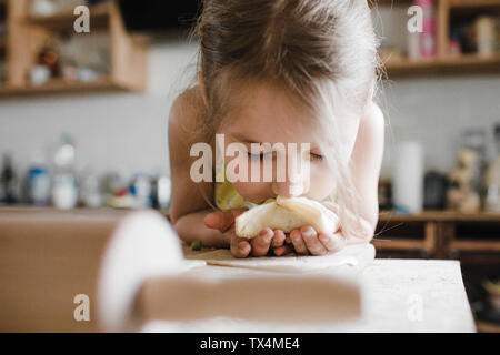 Little girl smelling freshly prepared stuffed pastry Stock Photo