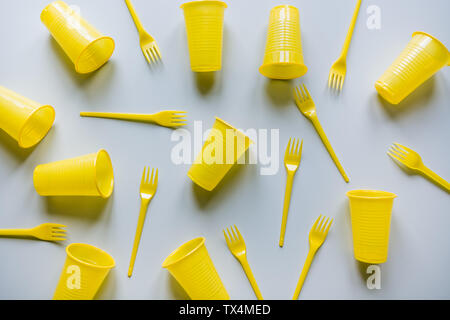 Disposable picnicyellow utensils on grey. Environment eco friendly discarded plastic garbage for recycle concept.Top view. Flat lay. Pattern. Stock Photo