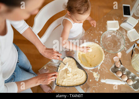 Top view of mother and little daughter making a cake together in kitchen at home Stock Photo