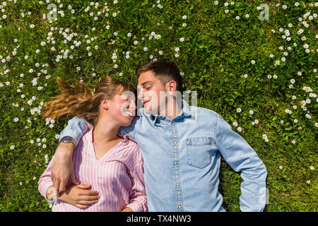 Happy young couple relaxing on grass in a park, overhead view Stock Photo