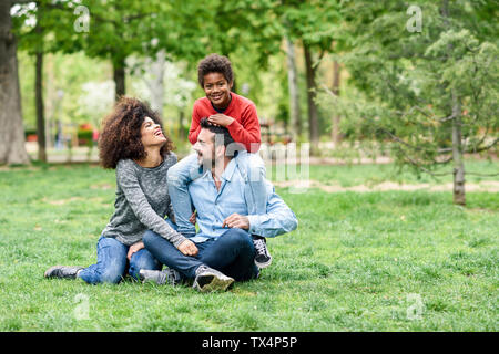 Happy family sitting on grass in a park Stock Photo