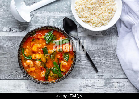 Red curry with sweet potato, yellow and red bell pepper, zucchini, sugar pea, shrimps and rice Stock Photo