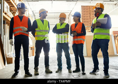 Smiling workers standing in factory workshop talking Stock Photo