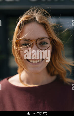 Portrait of happy young woman with glasses and windswept hair Stock Photo