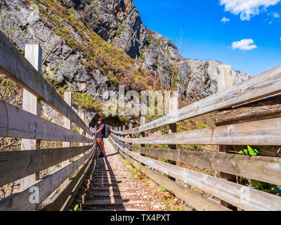 Spain, Asturia, Cantabrian Mountains, senior man on a hiking trip standing on a bridge