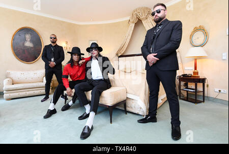 Munich, Germany. 24th June, 2019. The musical performers Koffi Missah (2nd from left) and Dantanio Goodman (3rd from left) sit, dressed as Michael Jackson, in the Hotel Bayerischer Hof on a bed in the 'Michael-Jackson'-Suite, in which the 'King of Pop' lived when he was in Munich. Next to them are two bodyguards. The makers of the Jackson musical 'Beat it' have invited friends and companions to the Bavarian Court to commemorate Michael Jackson on the 10th anniversary of his death. Credit: Tobias Hase/dpa/Alamy Live News Stock Photo