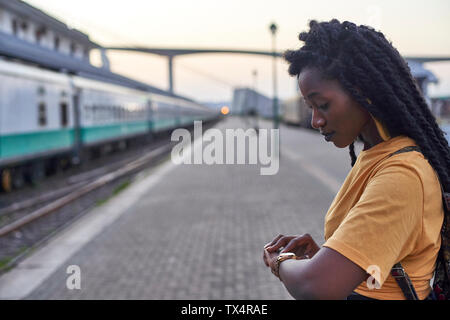 Young woman on platform at the train station checking her watch Stock Photo