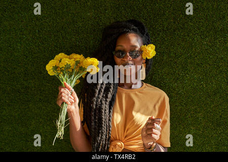 Young woman with dreadlocks holding flowers Stock Photo