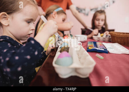 Girls painting Easter eggs on table at home Stock Photo