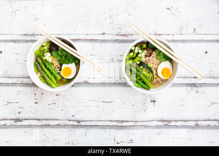 Two bowls of Ramen soup with egg, green asparagus, noodles, shitake mushroom and spring onions Stock Photo