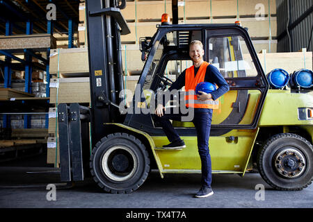 Portrait of happy worker at forklift in factory Stock Photo