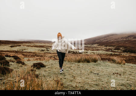 UK, Scotland, Isle of Skye, happy young woman running in rural landscape Stock Photo