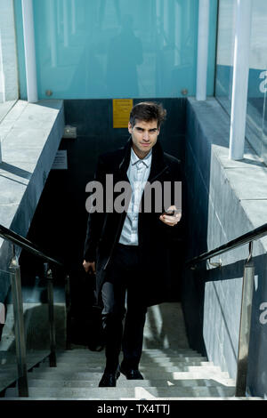 Businessman with cell phone walking up stairs in the city Stock Photo