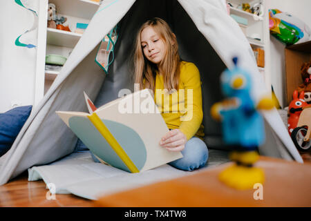 Girl at home reading book in children's room Stock Photo