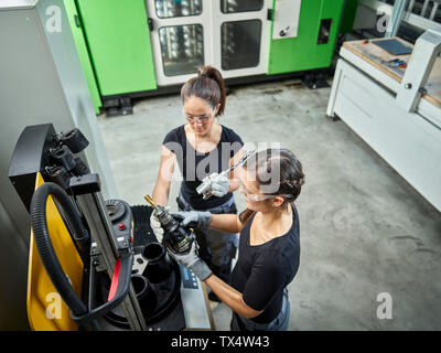 Two women working on a machine Stock Photo
