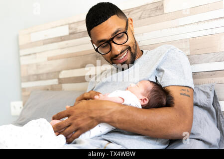 Happy father holding his newborn baby in bed Stock Photo