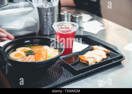 Ramen soup with pork dumplings on a plastic tray in a Japanese fast food cafe. The concept Asian lunch or dinner. Stock Photo